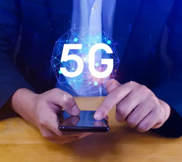 Dłoń na smartfonie, symbol 5G nad nim. Dowiedz się, jak wyłączyć 5G w telefonie, aby kontrolować połączenie.