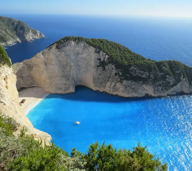 Grecja gdzie na wakacje? Zatoka Wraku na Zakynthos, z turkusową wodą i klifami, idealne miejsce na niezapomniany urlop.