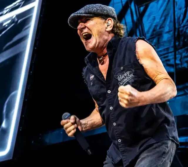 Brian Johnson z AC/DC w Polsce, w szczytowej formie, śpiewa z mikrofonem w dłoni.