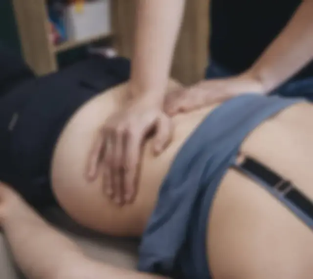 Fizjoterapeuta masuje plecy pacjenta.