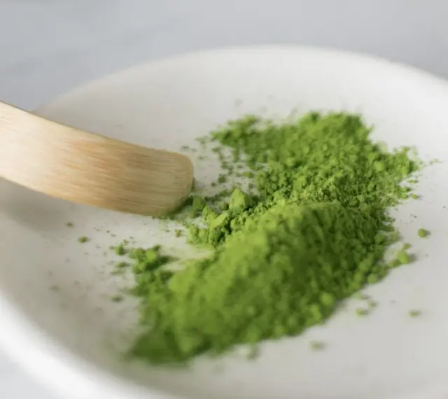 Zielony proszek matcha na białej miseczce, gotowy do przygotowania napoju. Poznaj, jak smakuje matcha – intensywnie, lekko gorzko, z nutą słodyczy.
