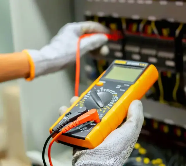 Elektryk sprawdza instalację multimetrem. Poznaj wymiana instalacji elektrycznej koszt i dowiedz się, jak uniknąć nieprzewidzianych wydatków.