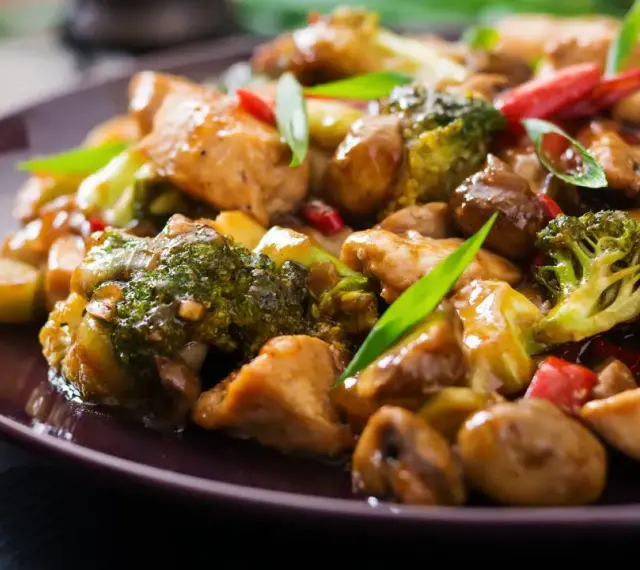 Pyszny stir fry z kurczakiem, brokułami i grzybami w sosie. Danie wygląda apetycznie i jest bogate w kolory.