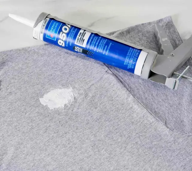 Zaschnięty silikon na szarym T-shircie i pistolet do jego aplikacji. Dowiedz się, jak usunąć zaschnięty silikon z ubrania.