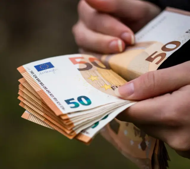 Dłonie trzymają stos banknotów 50 euro. Choć Bułgaria ma swoją walutę, euro jest powszechnie akceptowane.
