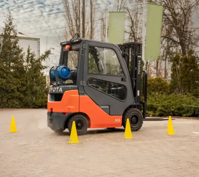 Pomarańczowy wózek widłowy Toyota na placu manewrowym. Idealne miejsce na kurs na wózek widłowy Kraków.