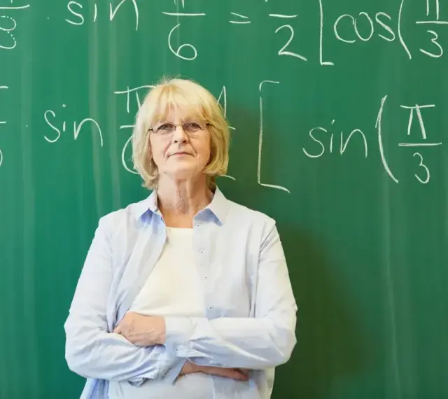 Nauczycielka matematyki przed tablicą z równaniami. Zatrudnienie nauczyciela po 1 września do kiedy umowa?