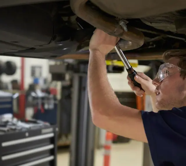 Mechanik naprawia układ wydechowy Renault, być może z powodu błędu DTC P0420.