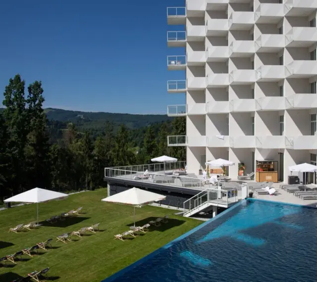 Nowoczesny hotel Crystal Mountain Resort z basenem i leżakami na trawie, otoczony zielonymi wzgórzami.