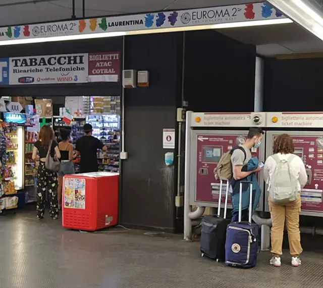 Przystanek autobusowy w Rzymie Ciampino. Ludzie kupują bilety i artykuły w sklepie.