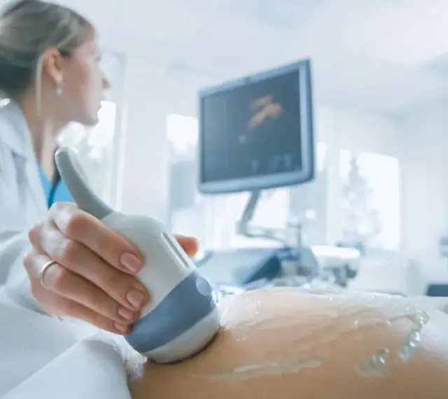 Lekarka wykonuje USG brzucha ciężarnej, monitorując przebieg ciąży. Badanie to jest kluczowe, zwłaszcza gdy stosowana jest heparyna w ciąży.