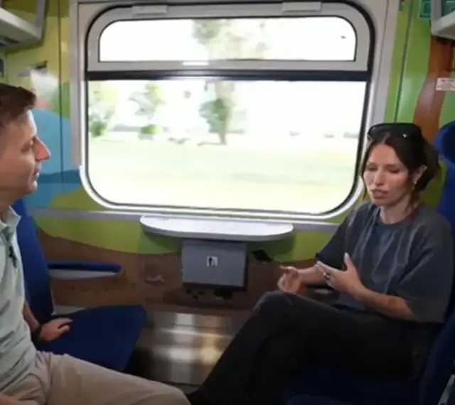 Rozmowa w wagonie z kolorowymi grafikami, być może w ramach specjalnego **metro programu** dla dzieci.