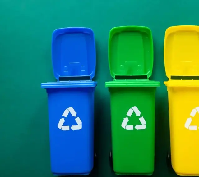 Trzy kolorowe kosze na śmieci: niebieski, zielony i żółty, z symbolami recyklingu. Pytanie: gdzie wyrzucać jednorazówki?