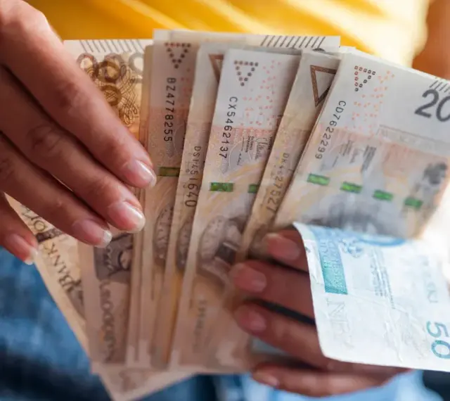 Dłonie trzymają plik banknotów 200 zł i 50 zł. Jak egzekwować obowiązek naprawienia szkody, gdy sprawca nie chce zapłacić?