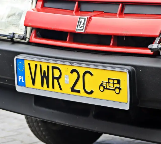 Czerwony grill z logo, reflektor i żółta tablica rejestracyjna z napisem VWR 2C oraz symbolem starego samochodu. To jest rejestracja dw.