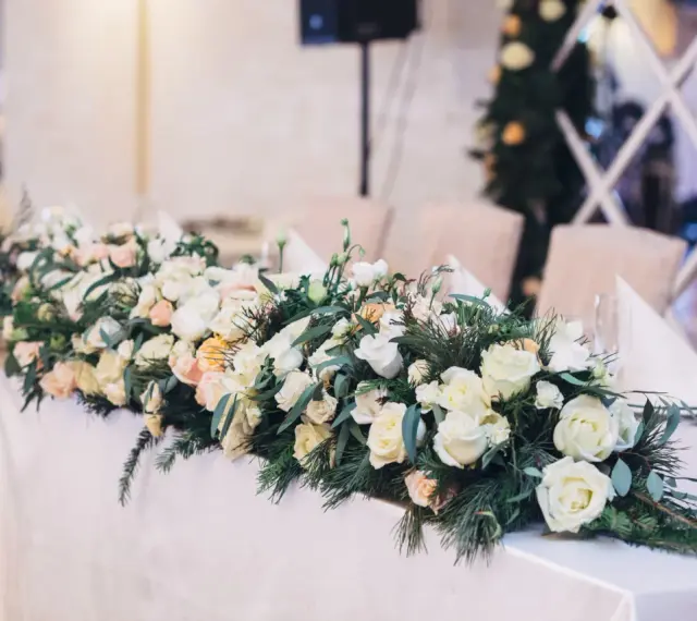 Eleganckie kwiaty na wesele zdobią stół, tworząc romantyczną atmosferę. Bukiet z róż i zieleni.