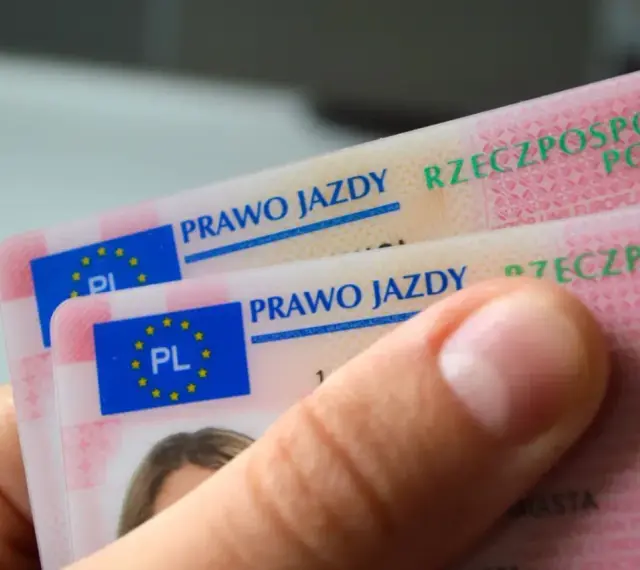 Dłoń trzyma polskie prawa jazdy. Widoczne napisy "PRAWO JAZDY" i "RZECZPOSPOLITA POLSKA" sugerują różne kategorie prawa jazdy.