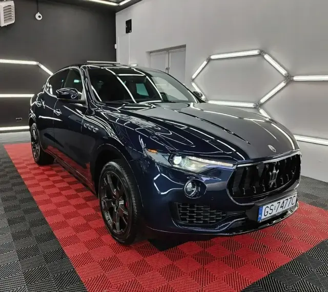 Lśniący, granatowy Maserati Levante na czerwono-czarnej podłodze. Sprawdź aktualną maserati levante cena i poczuj luksus.