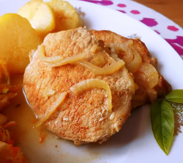 Pyszny schab w cebuli, idealny na niedzielny obiad, podany z ziemniakami i surówką.