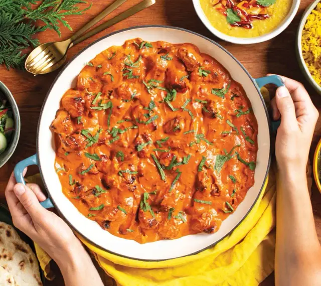 Pyszny **butter chicken przepis oryginalny** w kremowym sosie, podany z ryżem, sałatką i chlebkiem naan.