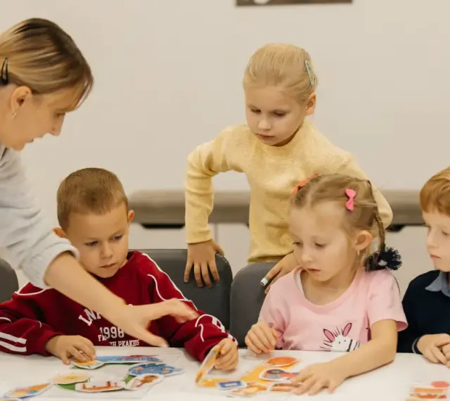 Nauczycielka pomaga dzieciom układać obrazki. Czy przedszkole może wypisać dziecko? Dzieci uczą się przez zabawę.