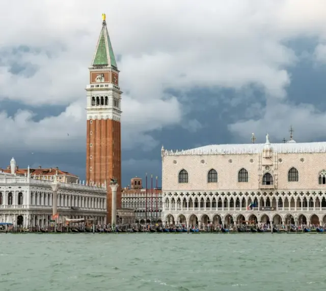 Weneckie budowle, w tym Pałac Dożów i Kampanila, na tle burzowych chmur. Venezia to miasto, które zachwyca.