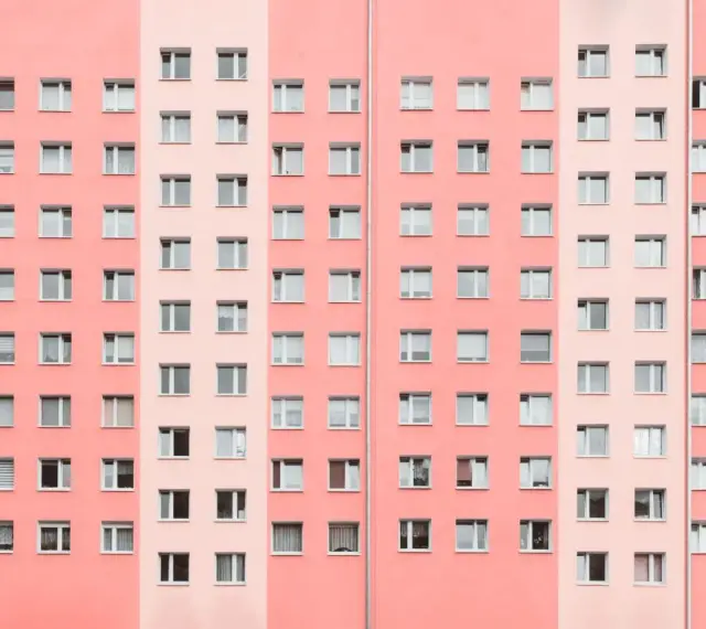 Pasteloza w architekturze: fasada bloku mieszkalnego w odcieniach różu i brzoskwini, z rzędami okien.