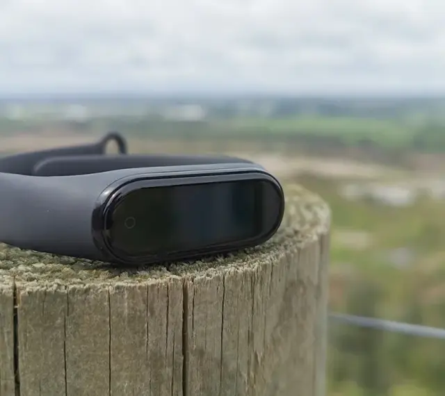Czarny Mi Band 4 na drewnianym słupku, idealny do śledzenia aktywności. To najlepsza aplikacja do Mi Band 4 dla aktywnych osób.