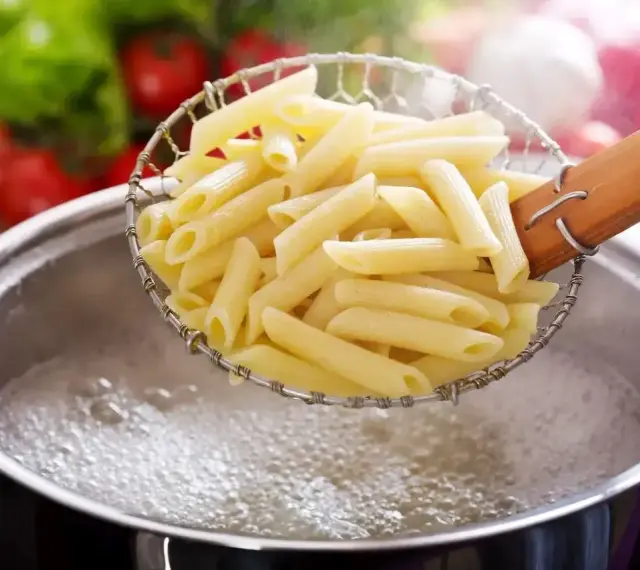 Penne makaron al dente, właśnie wyjęte z wrzątku, gotowe do sosu.