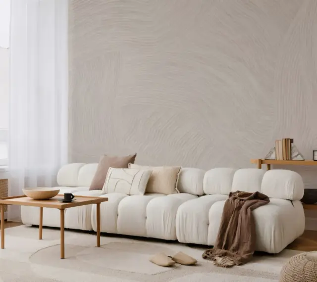 Minimalistyczny salon z sofą, stolikiem i lampą. Subtelne wzory na ścianie i dywanie podkreślają różnicę między stylem skandynawskim a japandi w oprawie eventu.