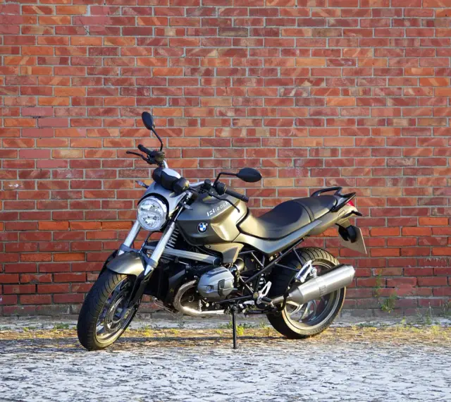 Szary motocykl BMW R1200R na tle ceglanej ściany. Poznaj jego dane techniczne i możliwości.