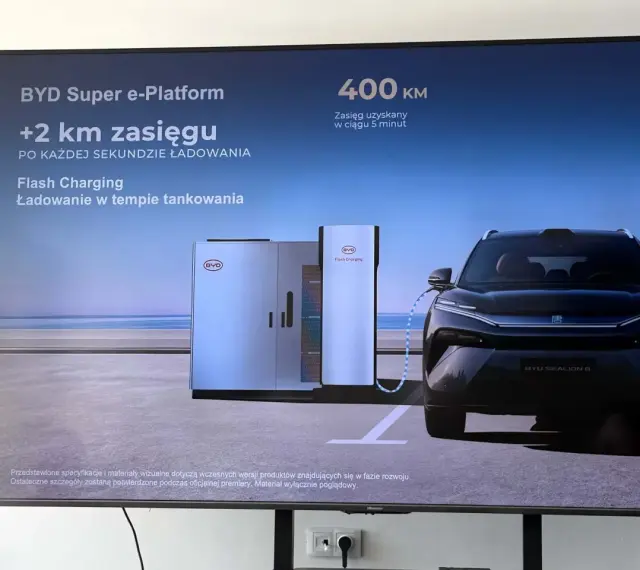 Czarny samochód elektryczny BYD Sealion 8 podłączony do stacji ładowania Flash Charging.