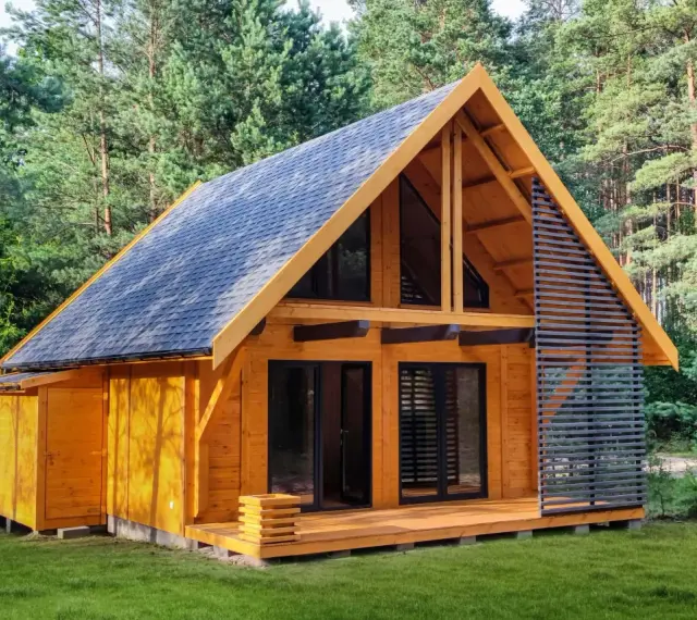 Nowy, drewniany dom letniskowy gotowy do zamieszkania, otoczony zielenią lasu.