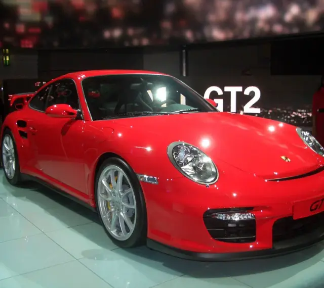 Czerwony Porsche 997 GT2 błyszczy na wystawie, gotowy do jazdy.