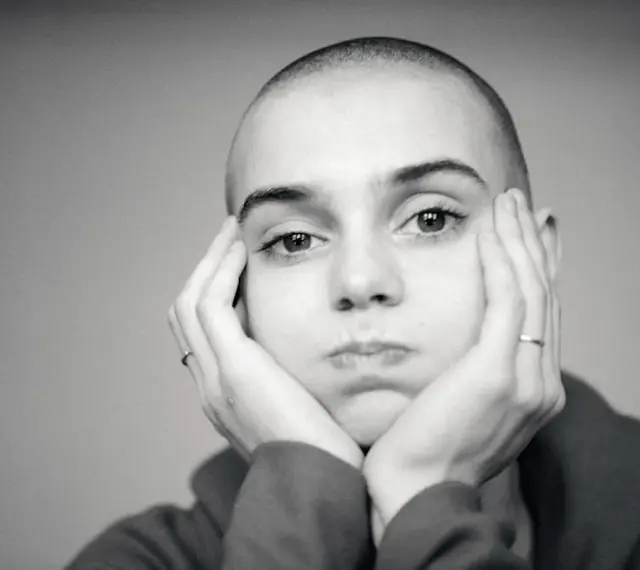 Sinead O'Connor z dłońmi opartymi o policzki, zamyślona.
