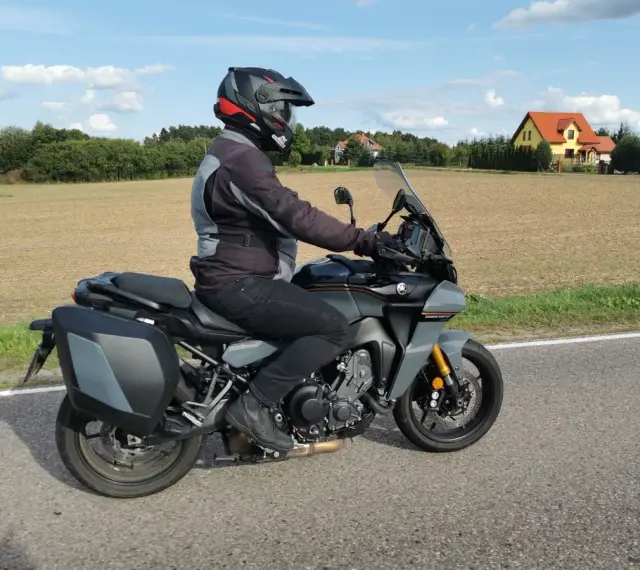 Motocyklista na Yamaha Tracer 900, z sakwami, w kasku, jedzie po drodze. Dane techniczne tego modelu są imponujące.