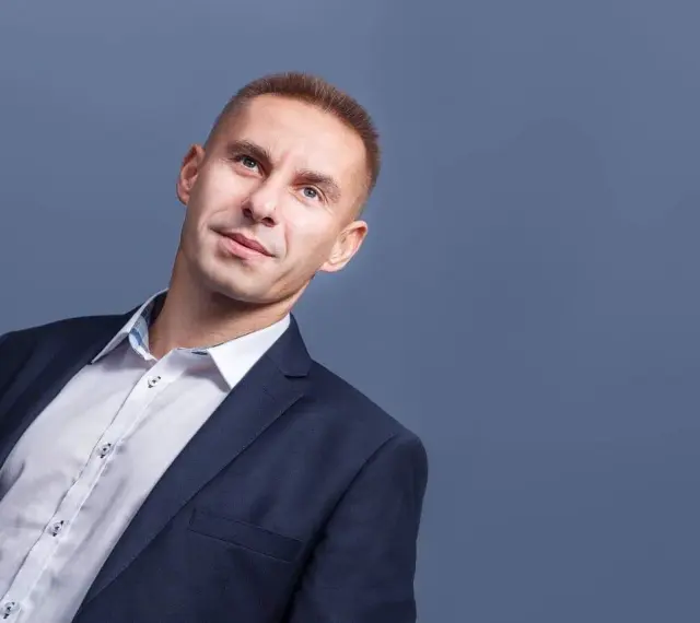Mężczyzna w garniturze i białej koszuli, patrzący w górę.