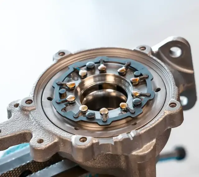 Metalowa obudowa turbosprężarki z widocznym mechanizmem kierownic spalin, kluczowym dla działania biturbo.