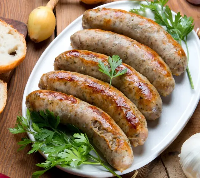 Pięć soczystych białych kiełbasek z piekarnika, podanych z chlebem, cebulą i czosnkiem.