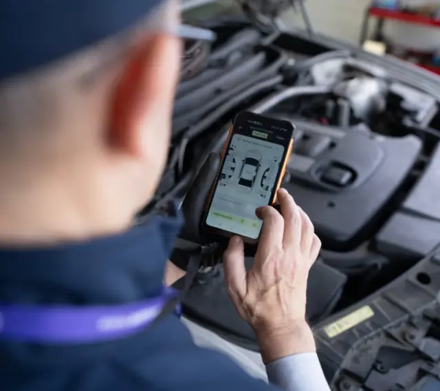 Mechanik sprawdza DTC BMW na smartfonie, analizując dane z silnika.