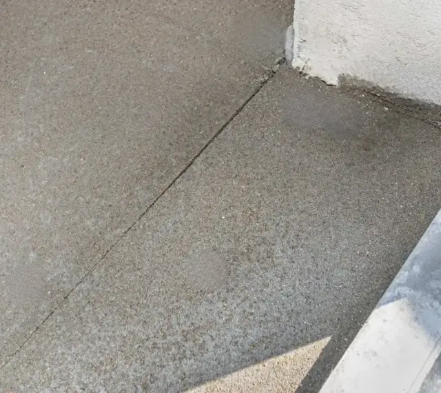 Szara posadzka betonowa z widocznym nacięciem, które zapobiega pękaniu. To właśnie jest dylatacja, która pozwala materiałowi pracować.