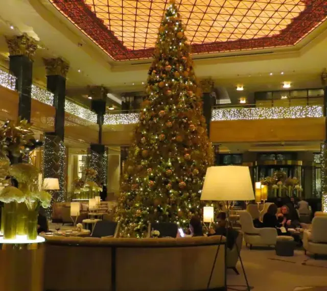 Elegancka wigilia w hotelu. Ogromna choinka i złote dekoracje tworzą świąteczną atmosferę.