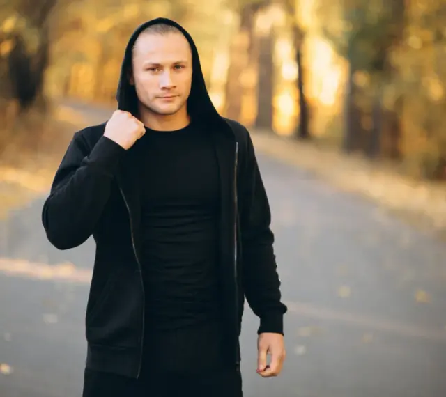 Mężczyzna w czarnej bluzie z kapturem i spodniami, idealny zestaw na fajne bluzy streetwear.