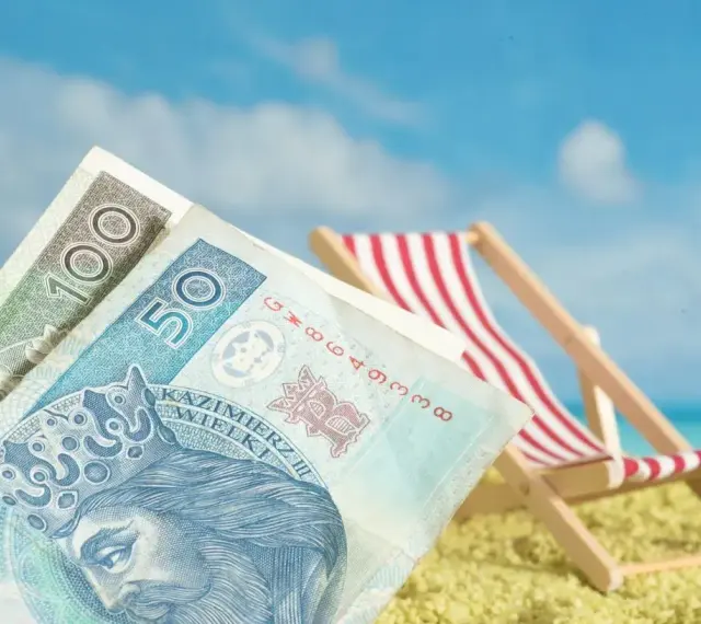 Pieniądze na plaży, leżak i błękitne niebo. To idealne połączenie, by cieszyć się zasłużonym świadczeniem urlopowym.