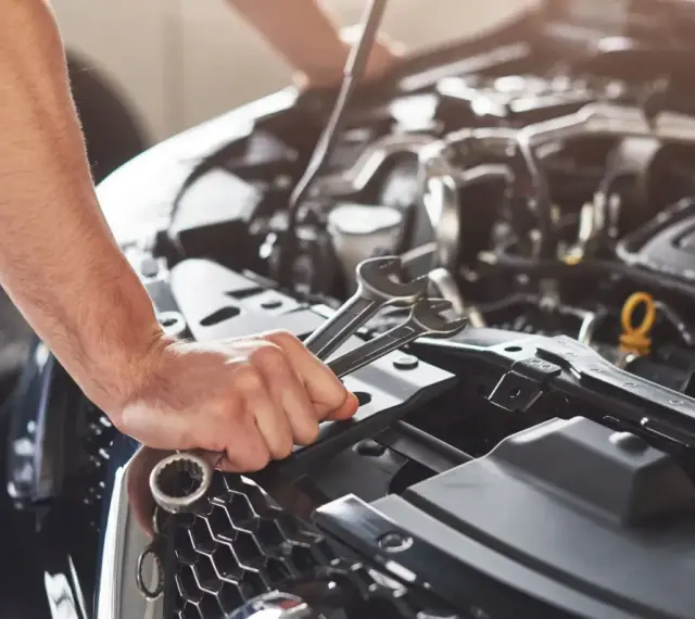 Mechanik sprawdza objawy awarii pompy paliwa Audi A4 B6 1.8T. W dłoni trzyma klucze.