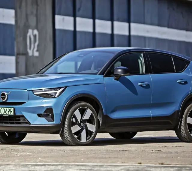 Niebieskie Volvo C40, elektryczny SUV coupe, parkuje przed budynkiem z numerem "02".