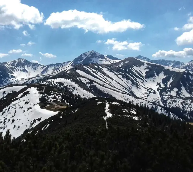Majestatyczne Tatry w kwietniu, pokryte śniegiem szczyty i zielone lasy.
