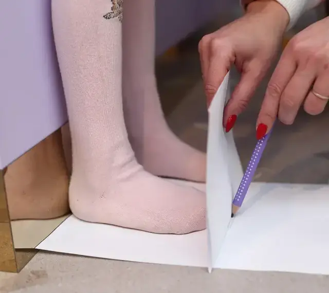 Dziecko mierzy stopę, by dowiedzieć się, jaki to rozmiar buta. 15 cm to idealny pomiar dla małych stópek.