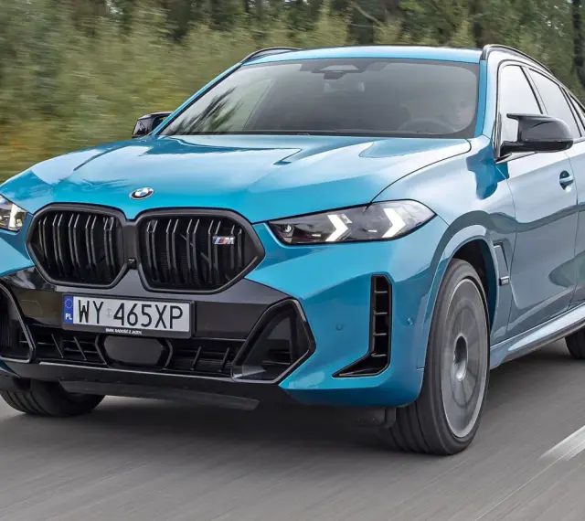 Niebieskie x6 BMW M na drodze, z rozmytym tłem lasu.