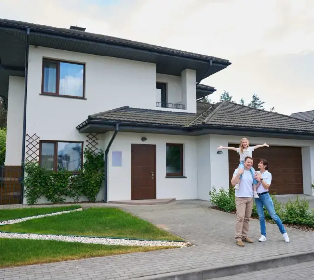 Szczęśliwa rodzina przed nowoczesnym domem. Realizacja marzeń o własnym M, gdzie koszt budowy domu 100m2 jest w zasięgu ręki.
